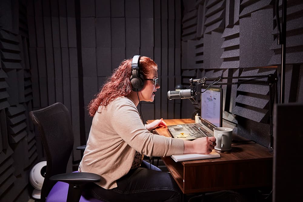 Female employee recording audio in a dedicated recording booth.